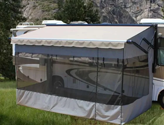 Screen room enclosing the space under a motorhome's patio awning at a wooded campsite